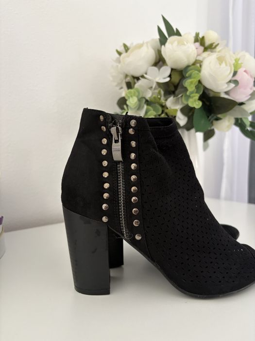 Vand botine negre din piele întoarsă au un design perforat și un vârf deschis.