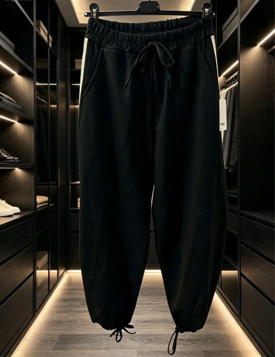 Modelul este larg (baggy), cu o talie elastică încrețită în partea de sus.