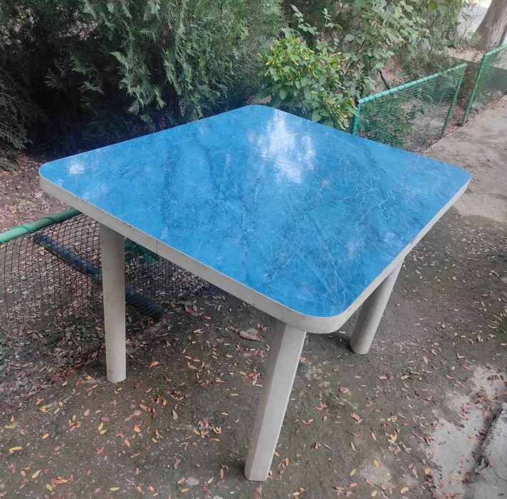 Кухонный Стол.  Столешница покрыта синим пластиком. Ножки деревянные.
