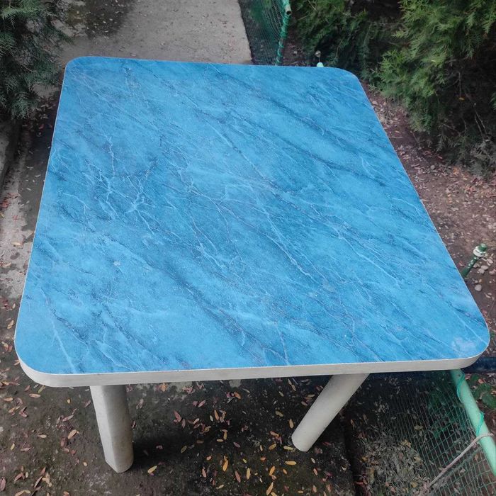 Кухонный Стол.  Столешница покрыта синим пластиком. Ножки деревянные.