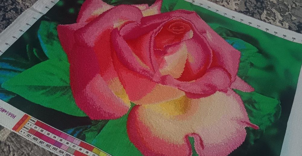 Вышивка крестом, изображающая крупный план розовой розы.