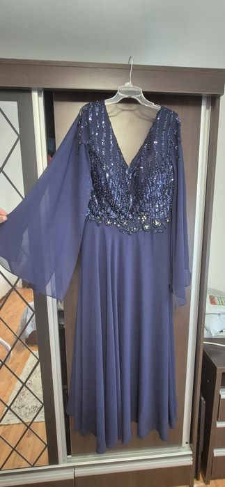 Rochie lungă de seară albastru închis, cu aplicații de paiete strălucitoare pe bust și mâneci lungi din voal.