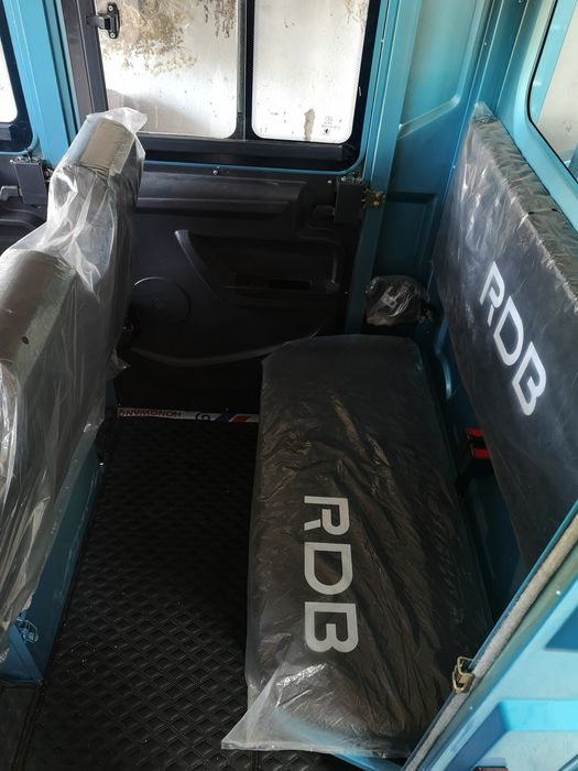 Triciclu electric utilitar cu cabină dublă și benă.