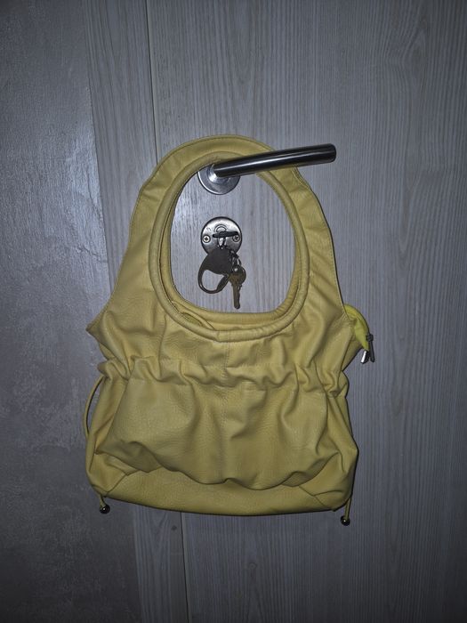 Жълта чанта с цип, вътрешен джоб и връзки за ефектно пристягане .