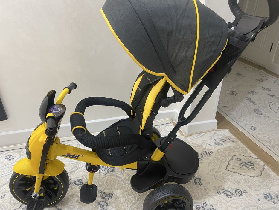 детский трёхколёсный велосипед-коляска жёлто-чёрного цвета.