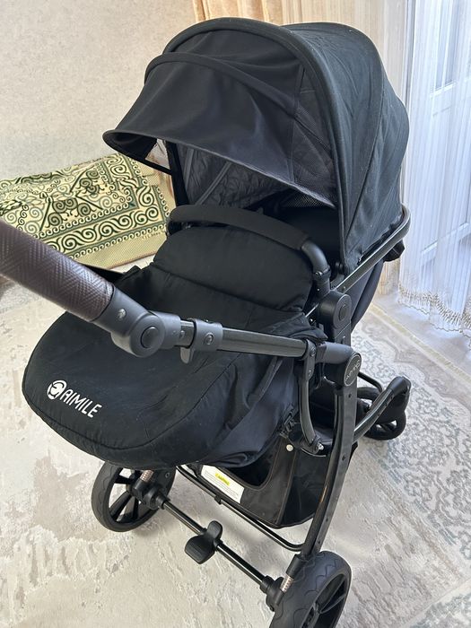 Продаётся современная детская коляска в чёрном цвете.