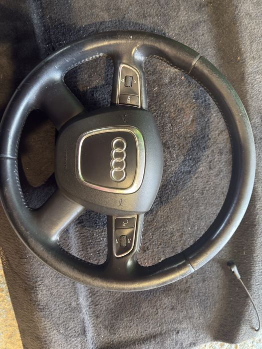 volan din piele cu 4 spițe și comenzi multifuncționale, specific pentru modele Audi (precum Audi A3 8P, A4 B8, A5, Q3, Q5 sau Q7)