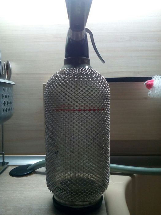 Голяма стъклена бутилка със сифон обвита с алуминий