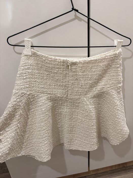 Бяла къса пола с висока талия и разкроен силует.