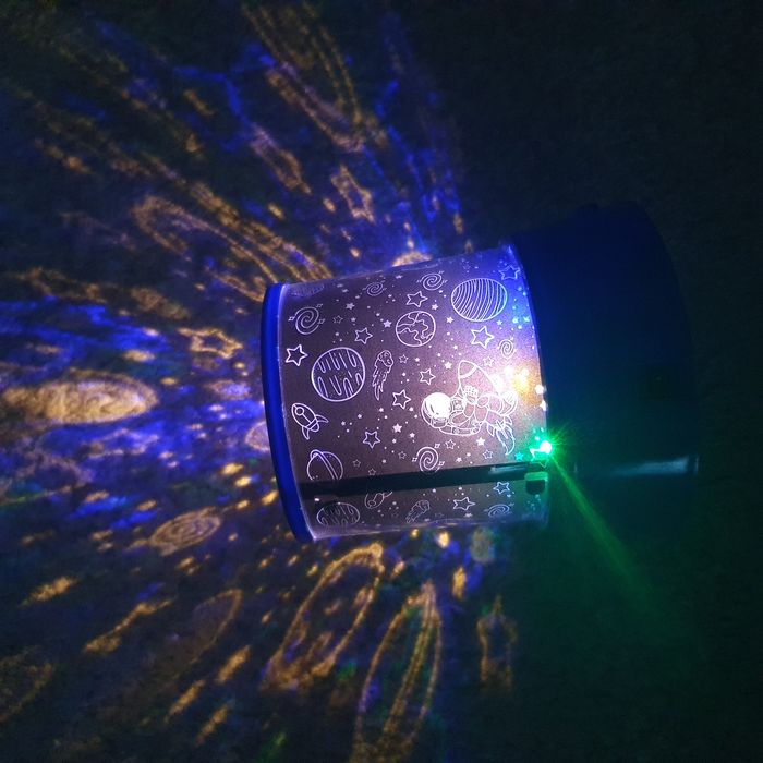 Lampa de veghe tip proiector, cu tematică de cosmos sau spațiu cosmic.