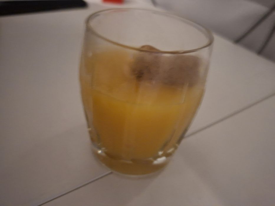 Pahar cu nectar de piersici și cu dop de vin spumant în el