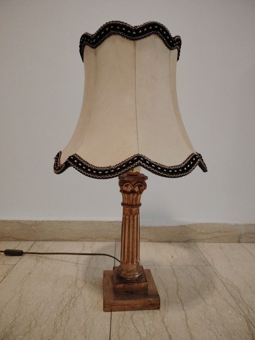Această candelabrului antic și elegant are o bază din lemn sculptată în stil Empire și Aba, iar abajurul este din material textil în nuanțe calde.