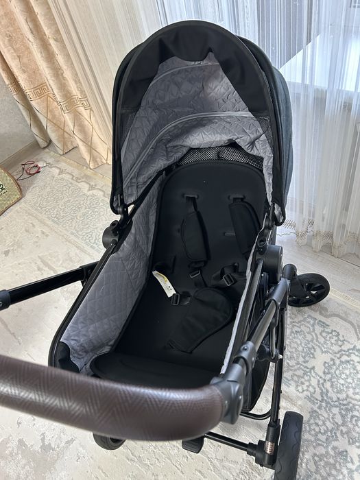 Продаётся современная детская коляска в чёрном цвете.