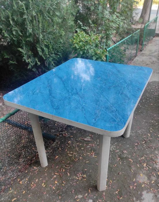 Кухонный Стол.  Столешница покрыта синим пластиком. Ножки деревянные.