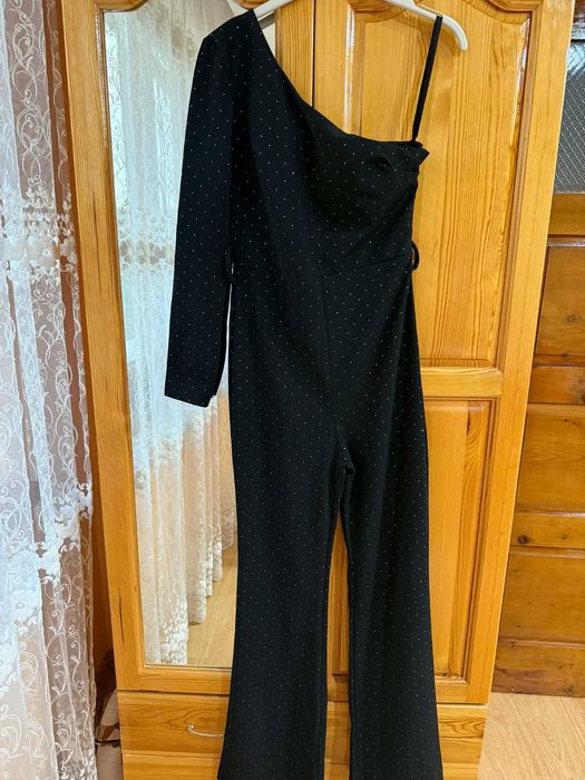 Ефектен гащеризон с един ръкав в черен цвят с фини декоративни точки.