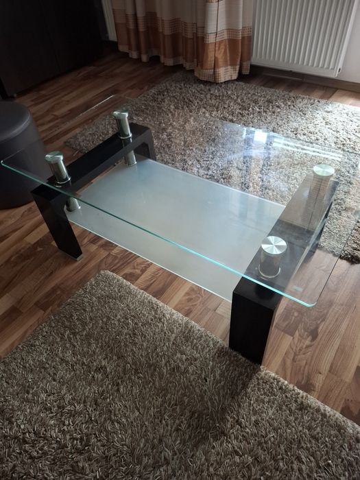 Măsuță de cafea modernă, realizată dintr-o combinație de sticlă, metal și lemn .