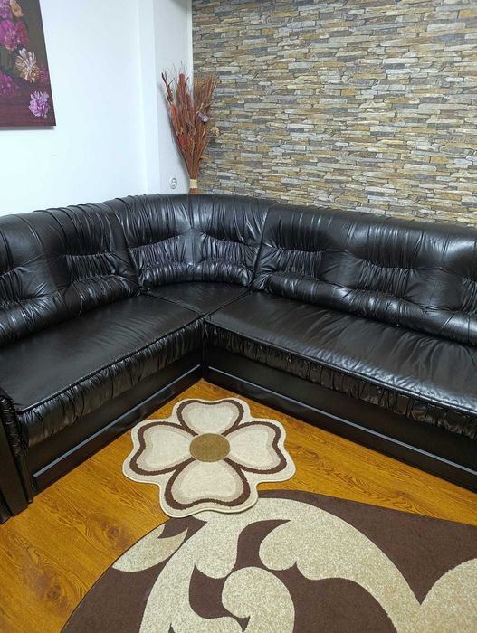 Vand coltar extensibil impreuna cu un fotoliu din piele neagra.