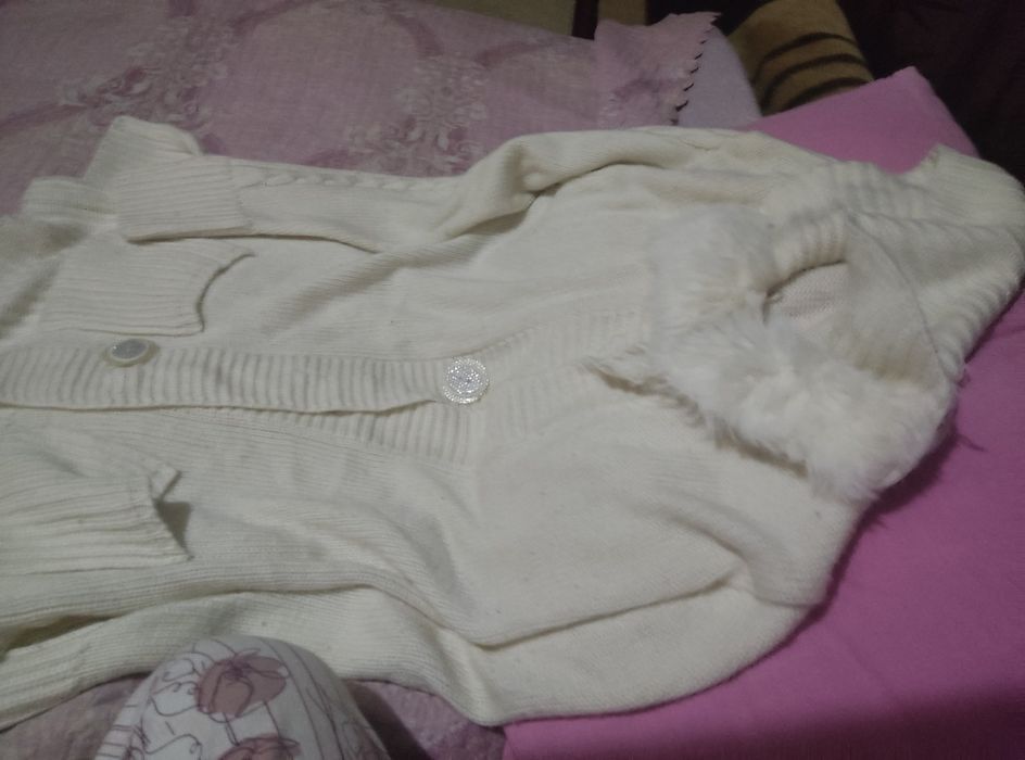 Это белый вязаный кардиган с пуговицами и воротником из искусственного