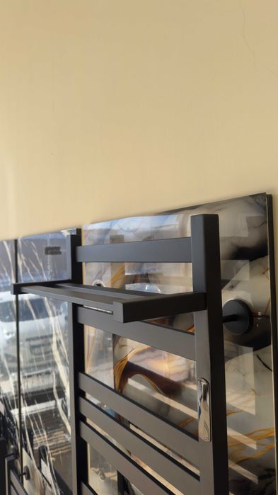 Полотенцесушитель с полочкой от производителя черного цвета.