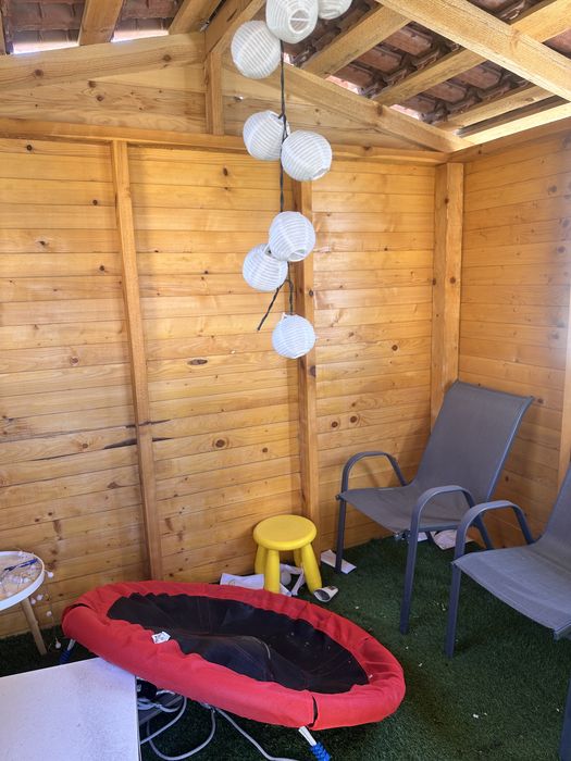 Дървена къща с пързалка и люлки.