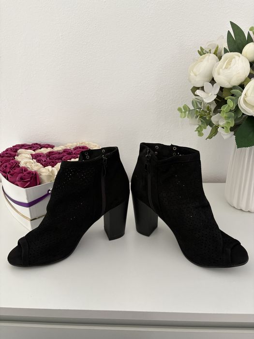 Vand botine negre din piele întoarsă au un design perforat și un vârf deschis.
