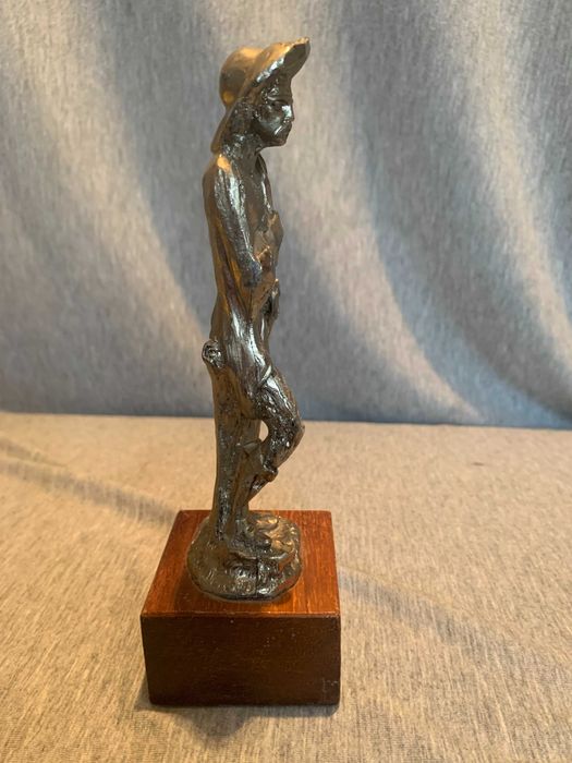 стара калаена статуя на човек с шапка върху дървена основа