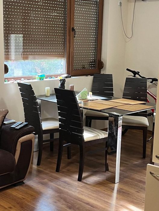 Трапезна маса от закалено черно стъкло с метални крака.