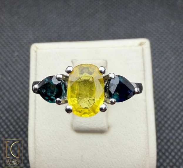 Inel din aur alb, decorat cu safir galben anturat de safire albastre