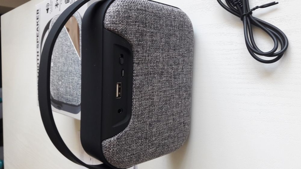 Блутут колонка говорител с текстилна обвивка и гумирана дръжка.