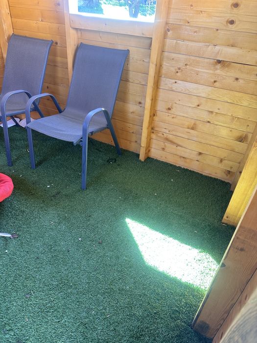 Дървена къща с пързалка и люлки.