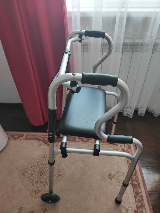 Vănd cadru de mers pliabil cu roți și suport pentru șezut.