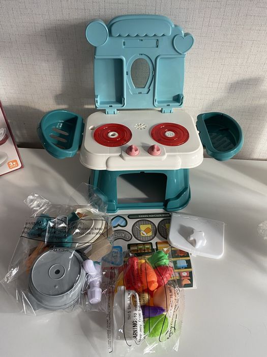 Малка зелена кухня със светещи котлони, пара и мивка с вода