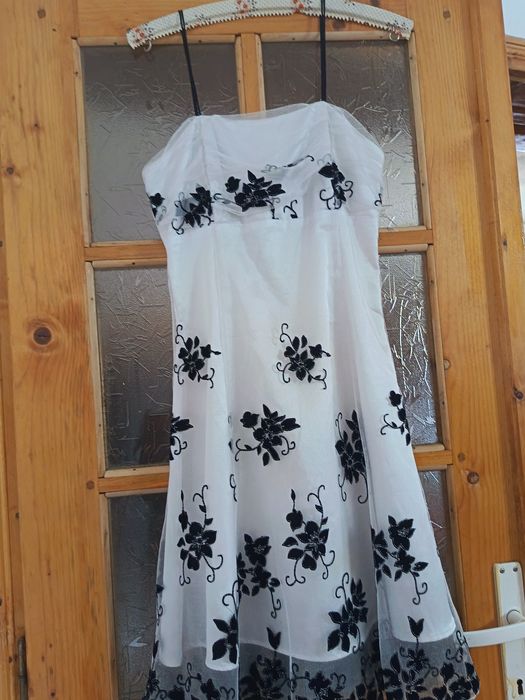 Rochie elegantă albă cu imprimeu floral negru.