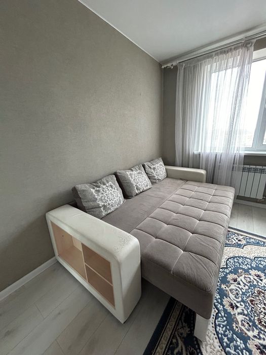 Диван серого цвета с белыми кожаными подлокотниками