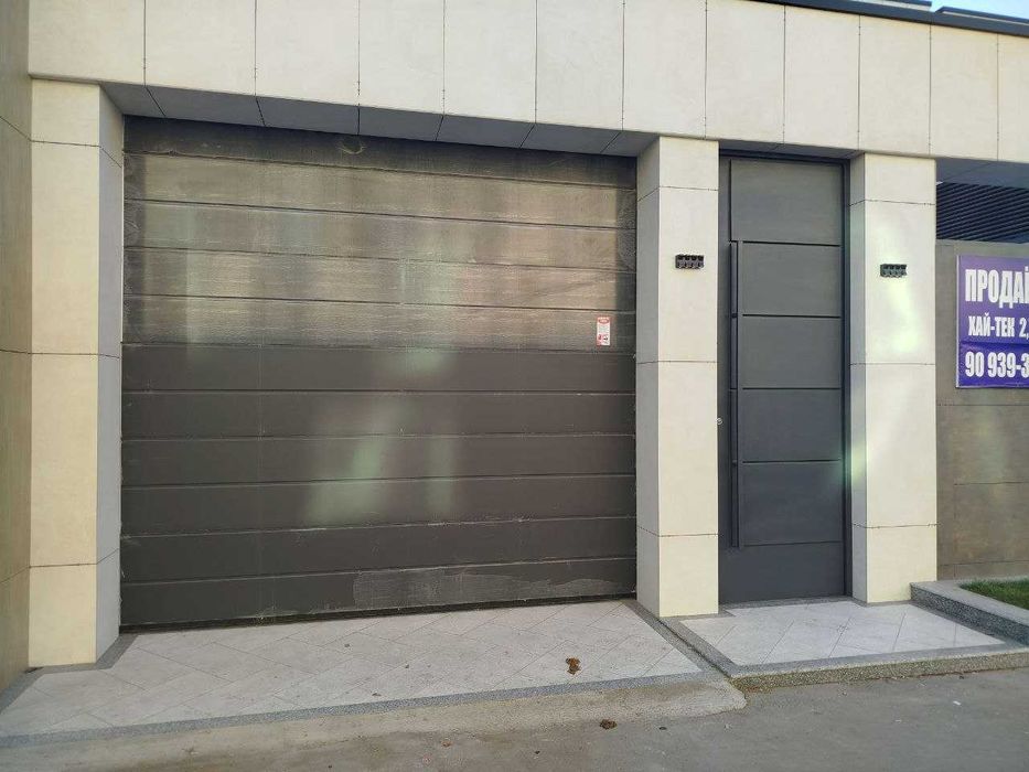 Входные двери в едином стиле с секционными воротами.