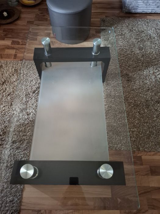 Măsuță de cafea modernă, realizată dintr-o combinație de sticlă, metal și lemn .
