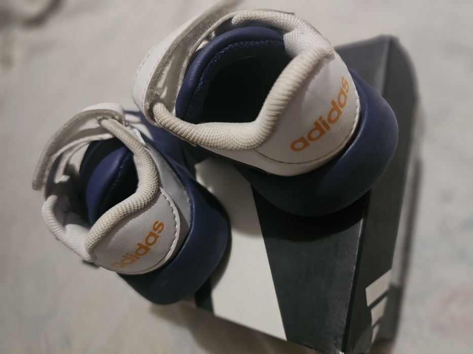 Това са детски бебешки маратонки Adidas  в бяло и тъмносин цвят.