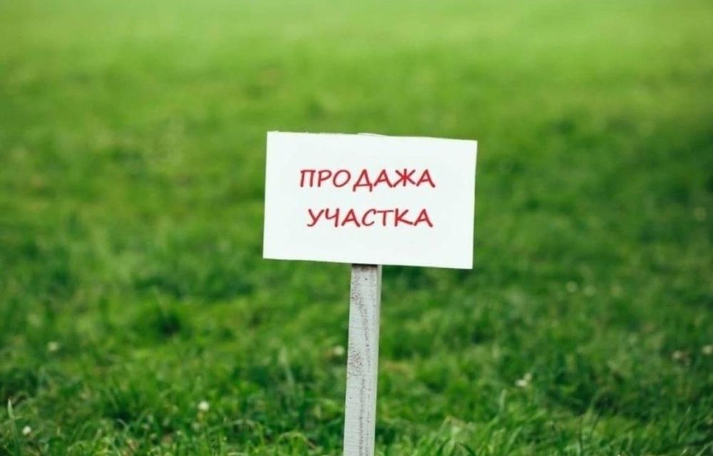 продавец держит табличку продано на фоне загородного участка