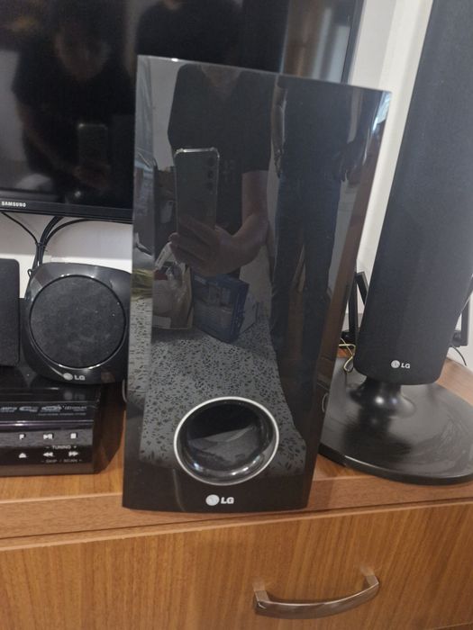SIstem Home Cinema LG 5.1 compus din boxe verticale de tip tallboy, un subwoofer, o boxă centrală, două boxe satelit mici poziționate pe unitate