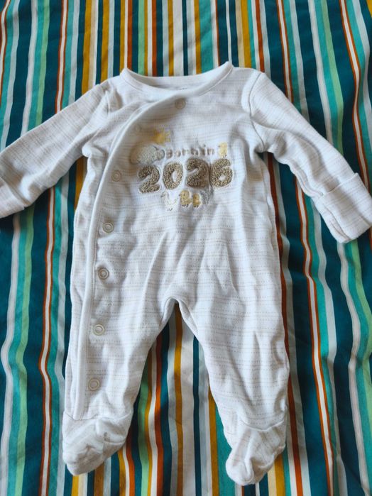 Продавам сладък бял гащеризон за новородено с надпис „Born in 2026“.