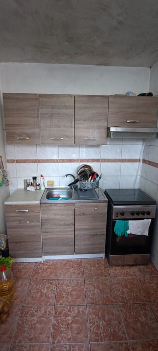 Mobilă de bucătărie, aragaz și hotă funcționale.
