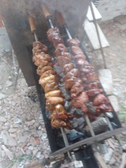 Барбекю на дървени въглища с въртящи се шишове и скара.