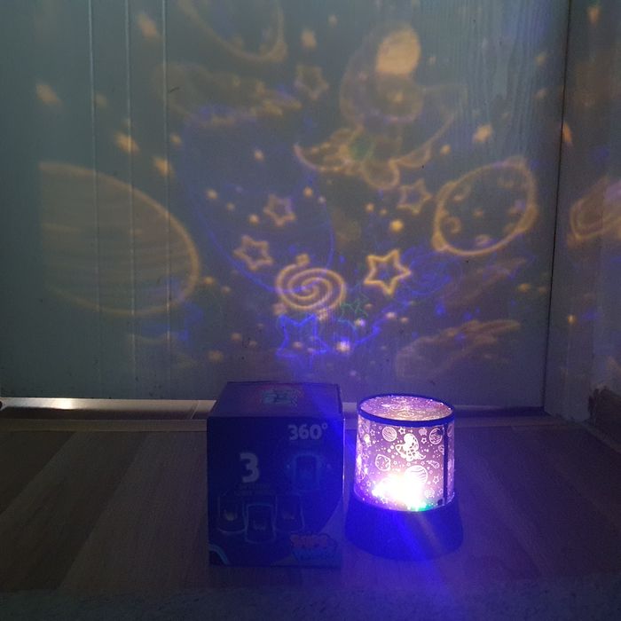 Lampa de veghe tip proiector, cu tematică de cosmos sau spațiu cosmic.
