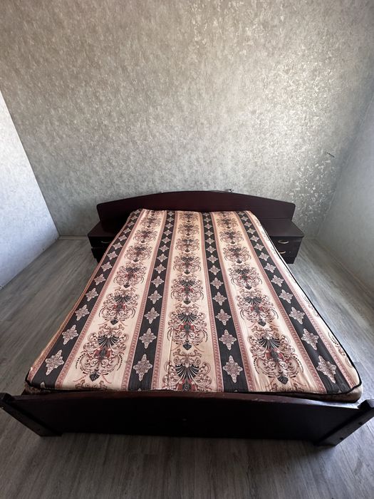 Кровать двуспальная имеет две прикроватные тумбочки