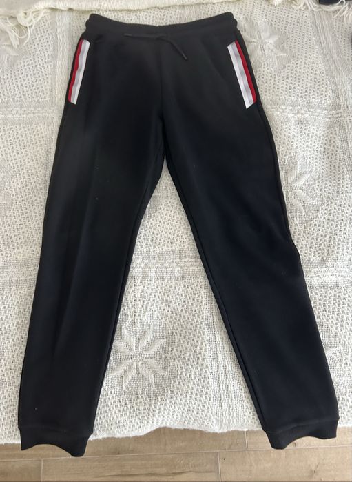 Trening Lacoste format din 2 piese pantaloni negri cu bluza roșie. mărimea M la bluză și mărimea S la pantaloni