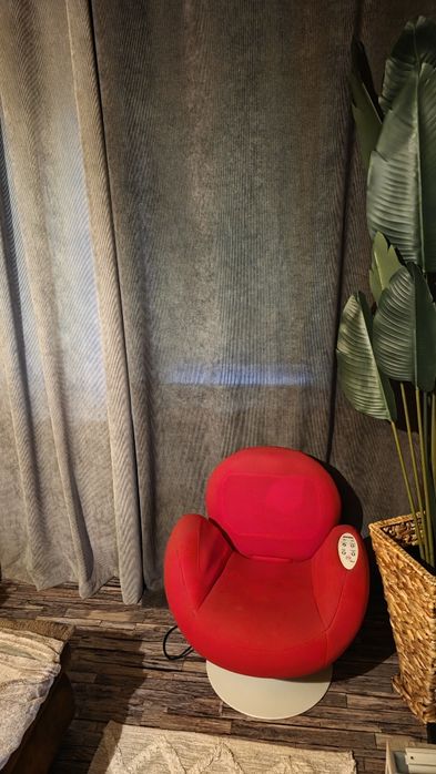 Scaun de masaj roșu cu funcții de rabatare și ridicare.