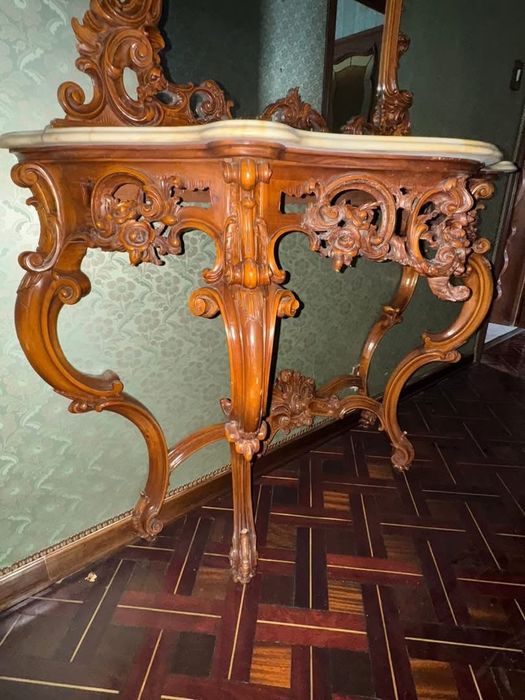 Consolă cu oglindă în stíl clasic baroc, realizată din Lemn masiv bogat sculptat manual, cu blat dín marmură naturală. Set impunător şi rafinat