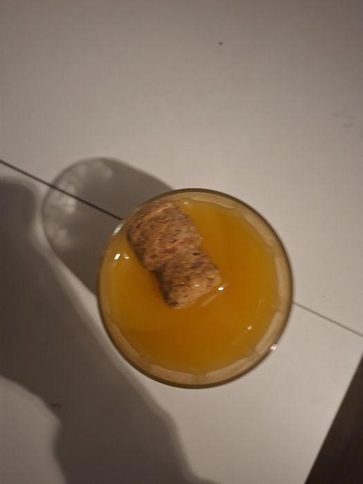 Pahar cu nectar de piersici și cu dop de vin spumant în el