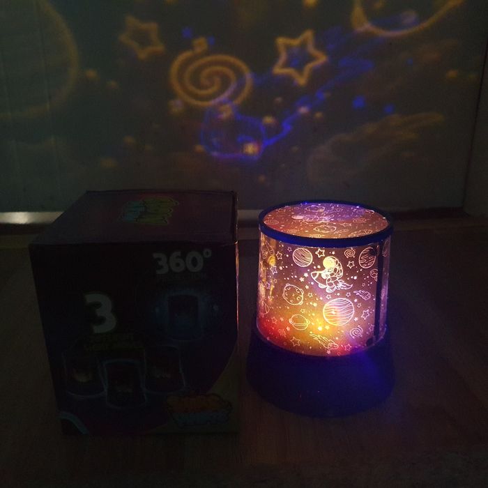 Lampa de veghe tip proiector, cu tematică de cosmos sau spațiu cosmic.
