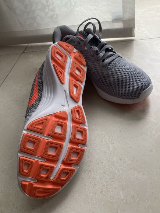Nike Revolution 3, având o culoare gri cu logo-ul portocaliu vibrant